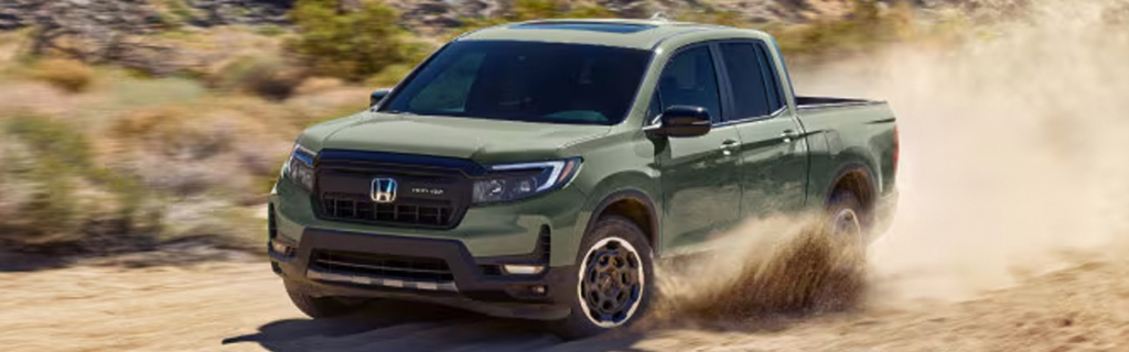 A green Honda Ridgeline truck driving through a dusty trail in a rugged landscape.
