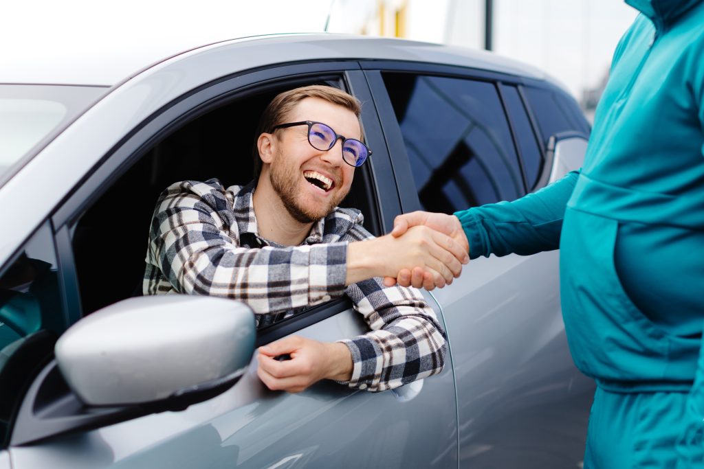 Smiling customer shaking hands car dealer