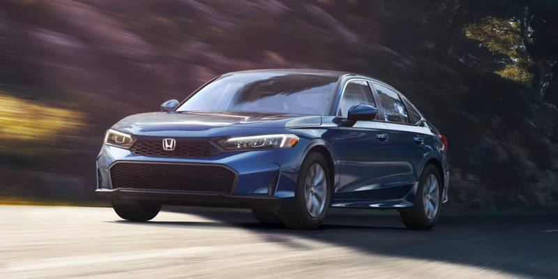 Blue Honda Accord sedan driving on a road with motion blur.
